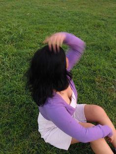 a woman sitting in the grass with her arms behind her head