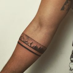 a man's arm with mountains and trees tattoo on the left side of his arm