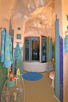 a bathroom with blue and green towels hanging on the wall next to a round tub