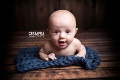 a baby is sitting on a blue blanket and looking at the camera with an excited look