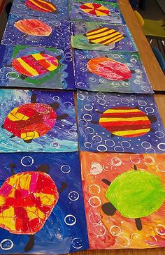 four colorful paintings on a table with water bubbles