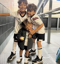 three young children are posing for a photo in front of an escalator with their arms around each other