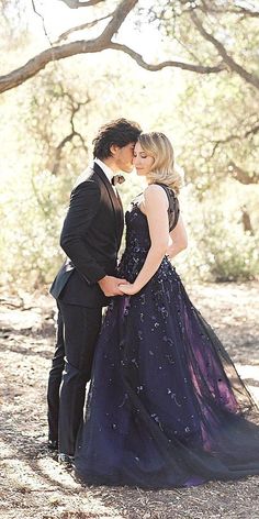 a man in a tuxedo kissing a woman in a purple dress