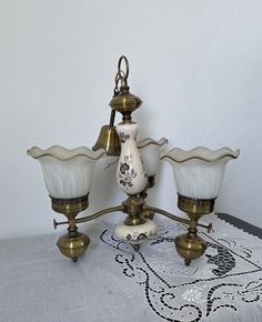 a table topped with three vases on top of a doily covered table cloth