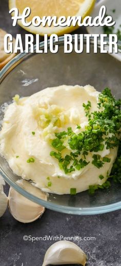 homemade garlic butter in a glass bowl with lemon wedges on the side and herbs sprinkled over it