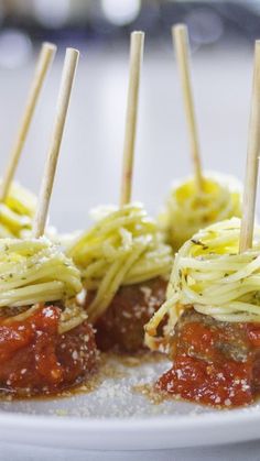 spaghetti and meatballs are served with toothpicks on a white plate, ready to be eaten