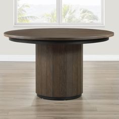 a round wooden table in front of a window