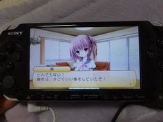 a person holding a video game controller in front of a screen with an anime character on it