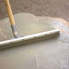 a trowel with a wooden handle on top of cement