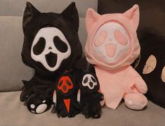 three stuffed animals sitting on a couch with one wearing a mask and the other as a cat