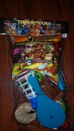 an assortment of toys in a plastic bag on a wooden table next to other items