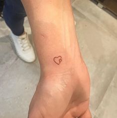 a small heart tattoo on the left wrist is shown in this image, it appears to be tiny