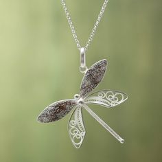 a silver necklace with a dragonfly pendant hanging from it's back end on a chain