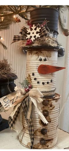 a snowman made out of tin cans is sitting in front of a christmas tree