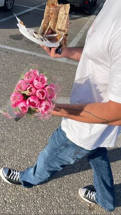 a man walking down the street with flowers in his hand and some crackers on top of him