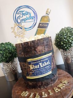 a cake made to look like a barrel with a bottle of blue label on top