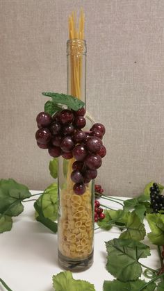 grapes and pasta in a glass vase on a table