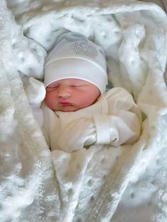 a newborn baby wrapped in a blanket and wearing a white knitted hat is laying on it's side