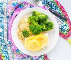 a white plate topped with broccoli and lemon slices