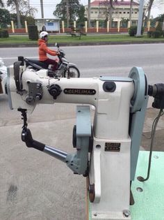 a person on a motorbike is operating a sewing machine in the middle of the street