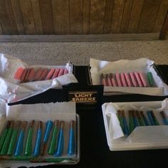 there are many different colored toothbrushes in the trays on the black table