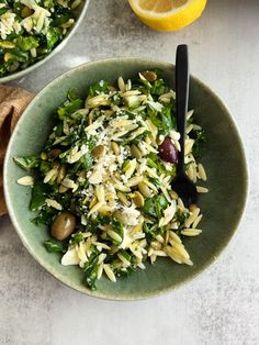 two bowls filled with pasta and vegetables on top of a table next to lemon wedges