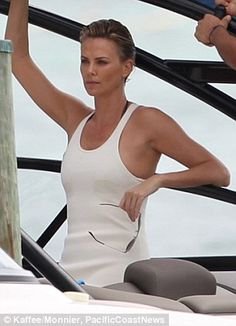 a woman in a white dress standing next to a man on a boat with his hand up