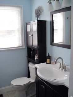 a white toilet sitting next to a sink in a bathroom under a window with blinds