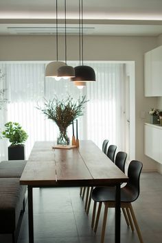 a dining room table with chairs and a vase filled with flowers on top of it