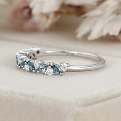 a close up view of a ring with blue stones and diamonds on the side, sitting on a white surface