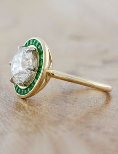 If you want old world charm with touches of deep green throughout the design - something fit for royalty - then you have found it in our Andora. We sourced a gorgeous 2.50ct brilliant round diamond for the center and sprinkled green emeralds that were custom cut to fit each and every nook and cranny of this beautiful halo ring. Setting cost only below:14k Rose, White, or Yellow Gold setting $9850 18k Rose, White, or Yellow Gold setting $10,100Platinum setting $10,350 This ring is not returnable, and requires up to 6 months for fabrication. Round Ring With Halo, Old Miners Cut Engagement Ring, Unique Colorful Engagement Rings, 1 Carat Engagement Ring Round, Round Emerald Ring, Halo Engagement Ring Emerald, Ring Upgrade, Vintage Wedding Ring, Halo Ring Setting