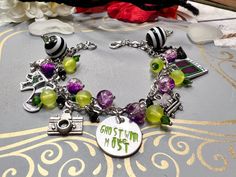 Beetlejuice bracelet has purple crackle glass beads, yellow frosted and green crystals, The end beads are black and white. The charms are a sandworm, beetle, photo, camera, house and sofa. Charms are made of shrink plastic and coated in UV resin. Bracelet is 8 inches but can be made any size. due to the handmade nature of the product there could be some variations in charms or beads but they will be as close to the photo as possible. Beetlejuice Bracelet Ideas, Beetlejuice Earrings Diy, Beetlejuice Bracelet, Beetlejuice Jewelry, Beetle Juice Earrings, Beetlejuice Accessories, Beetlejuice Fan Art, Beetlejuice Costume, Beaded Braclets