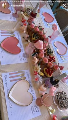 a table topped with lots of cupcakes covered in frosting and pink icing