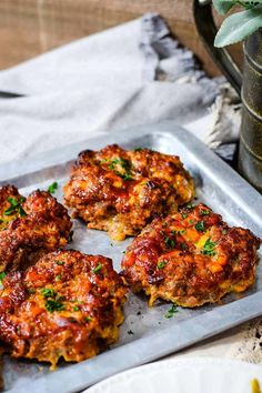 four crab cakes sitting on top of a metal tray next to a potted plant