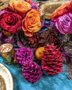 a table topped with lots of different types of flowers and pinecones on top of a blue cloth