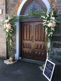 an entrance to a church decorated with flowers and greenery for a wedding ceremony or reception