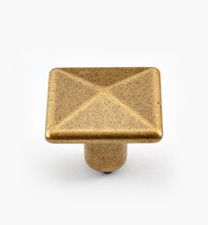 an antique brass square knob on a white background