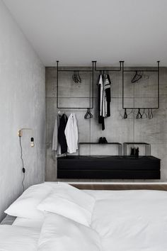 a bed with white sheets and pillows in a room next to a wall mounted coat rack