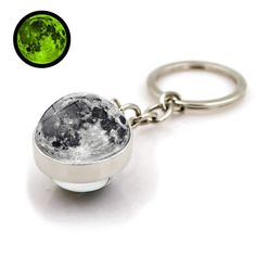 a keychain with a green and black moon in the center on a white background