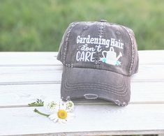 Need to change this cap design to a messy bun/high ponytail cap style, a non-distressed baseball cap or kid's baseball cap? Once you have this cap in your cart, head here: https://etsy.me/2S82fka Distinct Headwear Presents... 🌼Embroidered Gardening Hair Don't Care Cap. 🌼Main photos show: Dark grey base: White Text, Silver and White Watering Can, and Teal Flowers 🌼Order as shown or pick your custom flower color. ---->Please note all text will be white unless otherwise noted in the notes/per Baseball Cap Hair, Bun High, Ponytail Cap, Kids Baseball Caps, Gardening Hat, Monogram Hats, Distressed Baseball Cap, A Messy Bun, Custom Caps