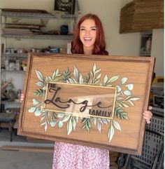 a woman holding up a wooden sign with the word love painted on it