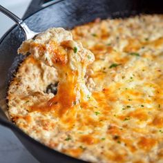 a close up of food in a skillet with a spoon sticking out of it