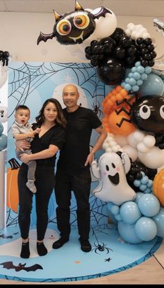 a man, woman and child standing in front of a balloon wall with halloween decorations