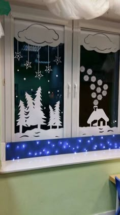 two windows with christmas decorations on them and blue lights in the window sill below