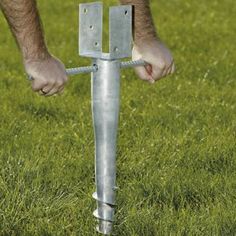 a man standing on top of a grass covered field next to a metal cross in the ground