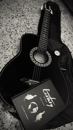 an acoustic guitar is laying on the floor next to its case and instruction manuals