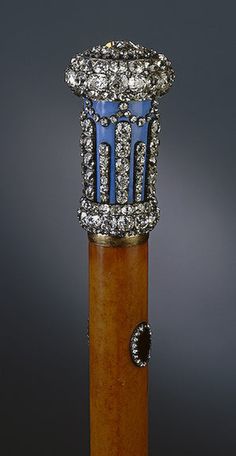 an antique wooden stick with blue and white stones on it's top, in front of a gray background