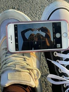 a person taking a selfie with their cell phone while standing on the ground in sneakers