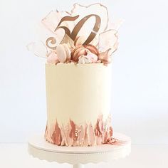 a white and pink cake with the number 50 on it's top is sitting on a stand