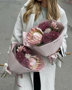 a woman holding two bouquets of flowers in her hands